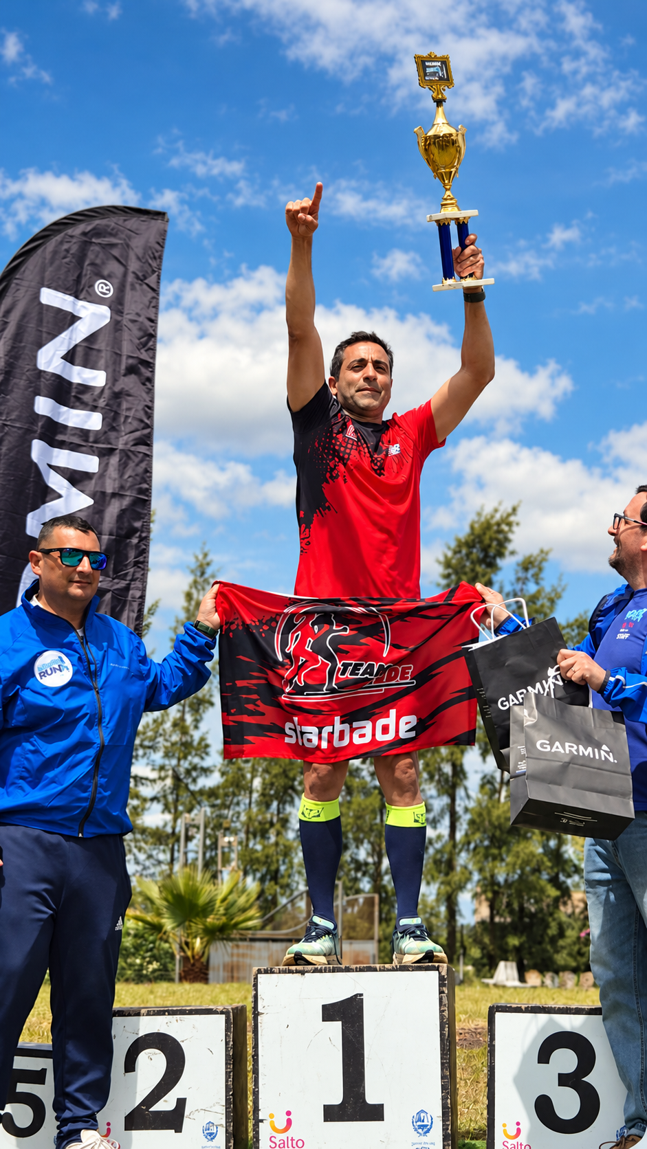 Juan Trinidad en el primer puesto del podio, levantando el trofeo con la bandera del Team Fede